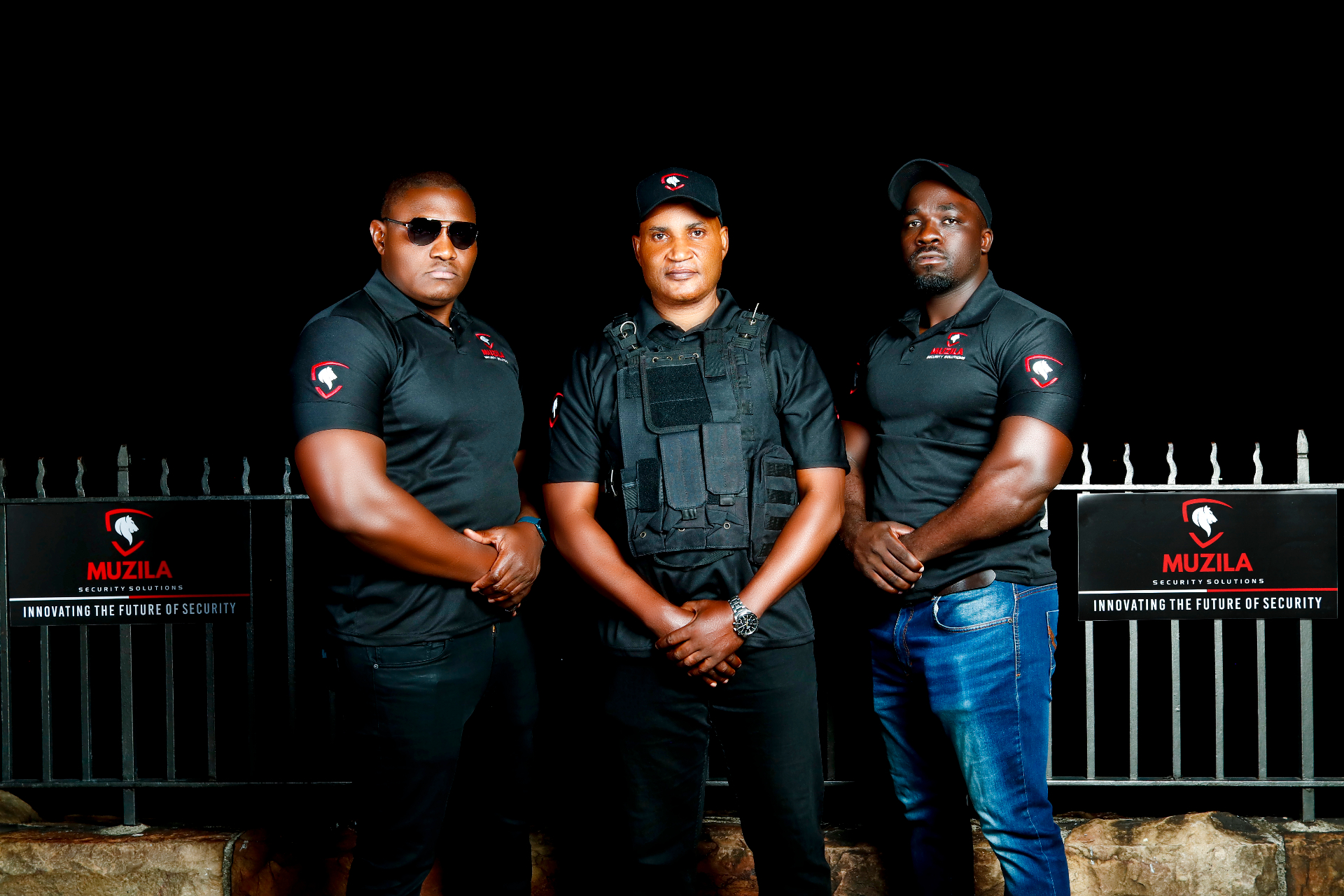 A trio of uniformed Muzila officers stationed at a corporate entrance, calm and observant during a daytime shift.