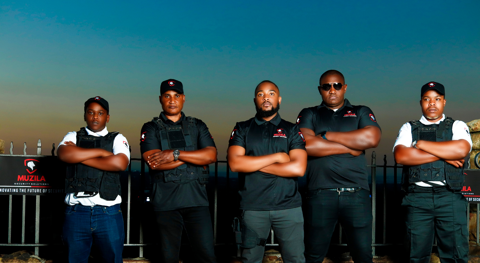 Five Muzila Security Solutions officers standing in formation at dusk, silhouetted against a Johannesburg sunset — the opening frame of the operators film.